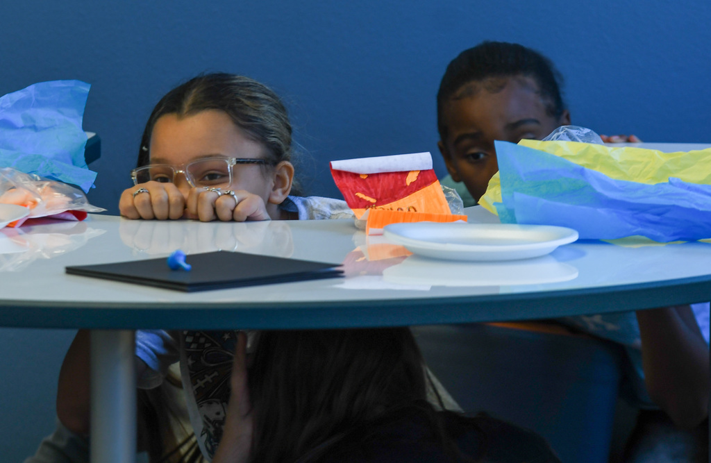 students performing a play, peaking out from hiding behind a desk