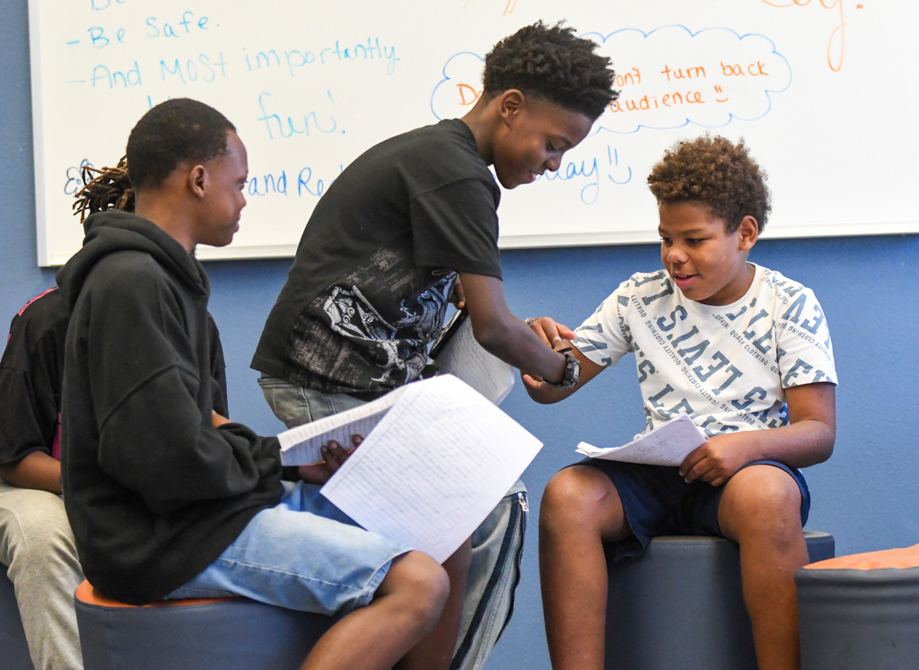 students performing a play, a boy takes another boys arm