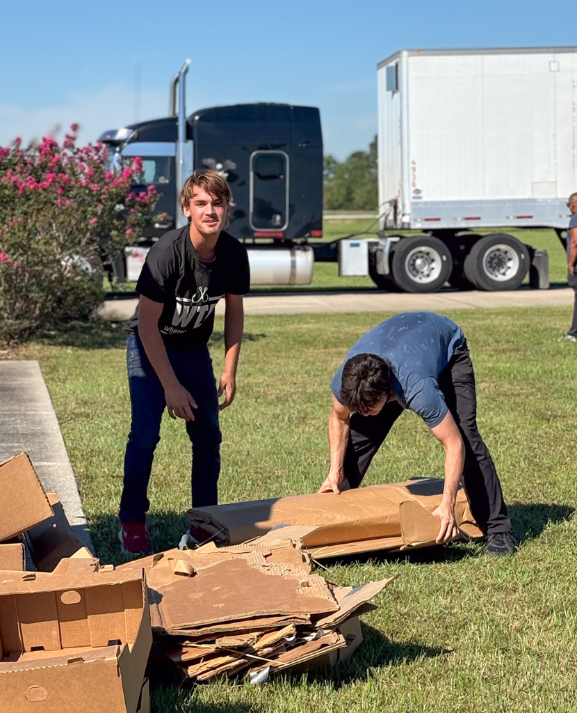 two male students picking up cardboard scrap at pumpkin patch