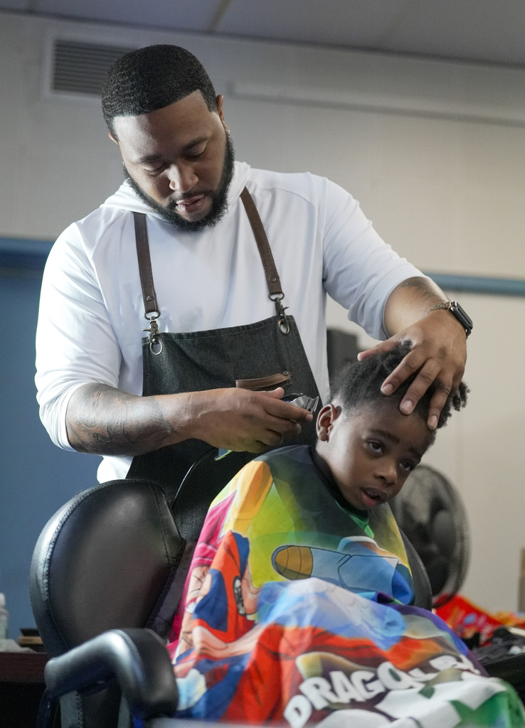 barber using a shaver on a boys hair