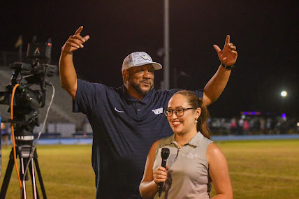 coach hickman raising his hands in celebration before a news interview