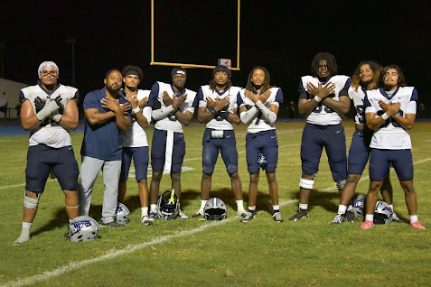 football players and a coach posing for a group photo