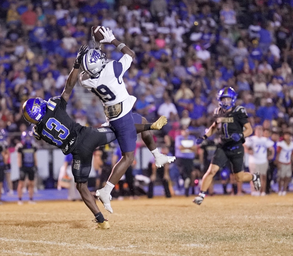 #19 catches the ball in the air as two defenders fail to stop him