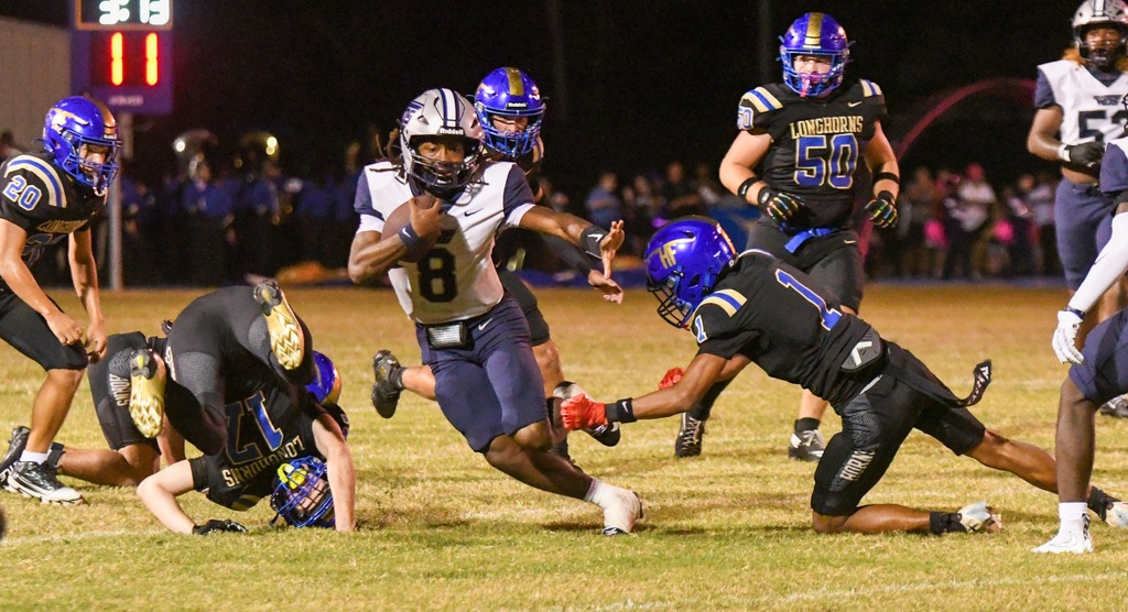 QB #8 dodges defenders while carrying the ball