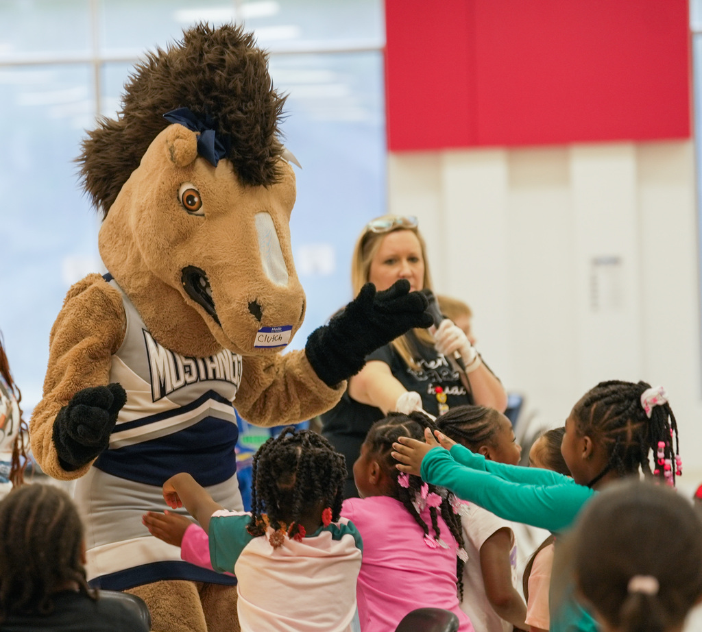 students reaching out to hug WOSHS Mascot Clutch