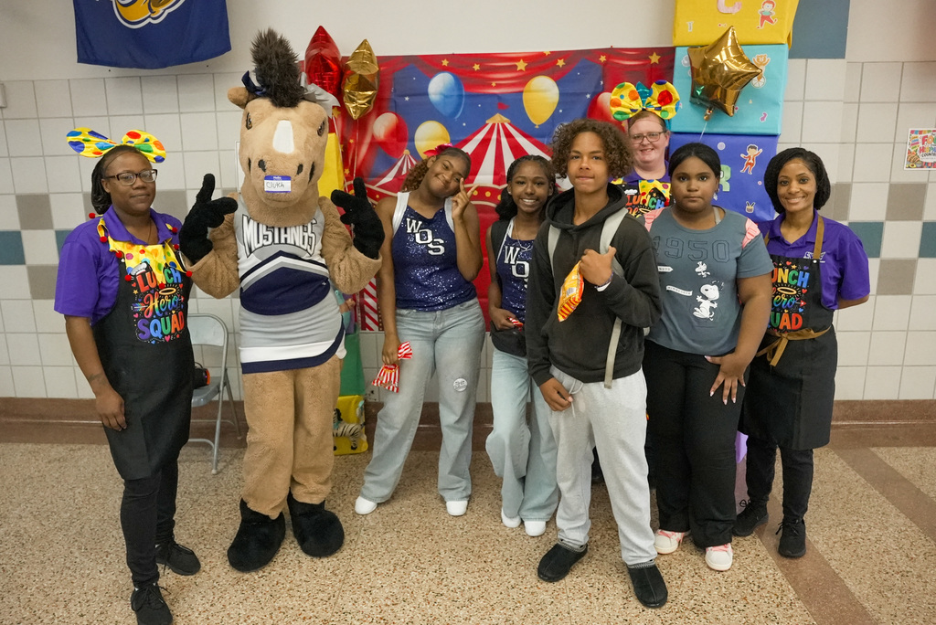 WOSHS Mascot Clutch poses with WOSMS cafeteria staff and student drawing winners