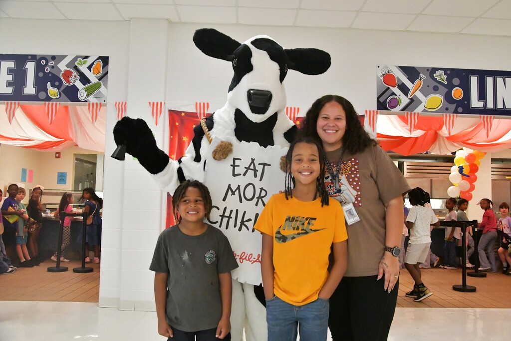 WOSE teacher with two brothers taking a picture with Cow the Chick-Fil-A mascot