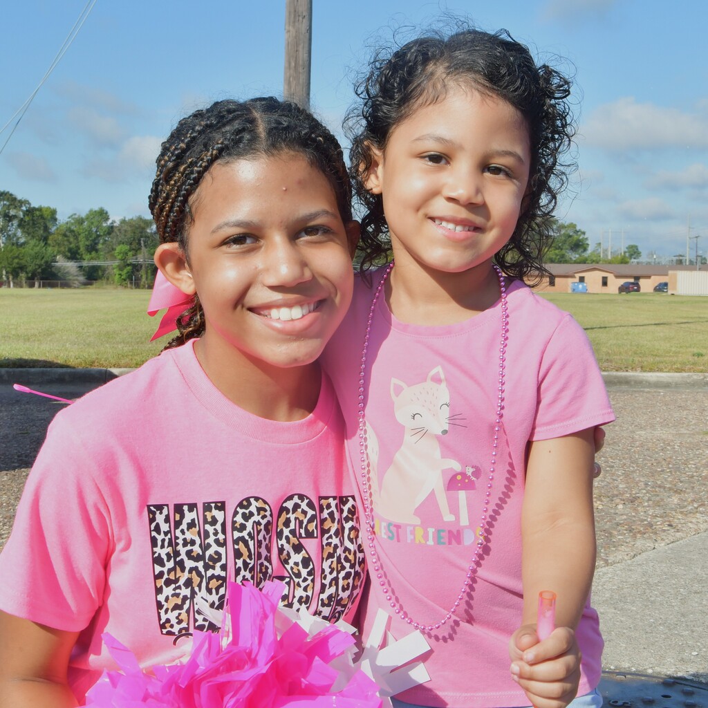 Two sisters wearing pink shirts smiling