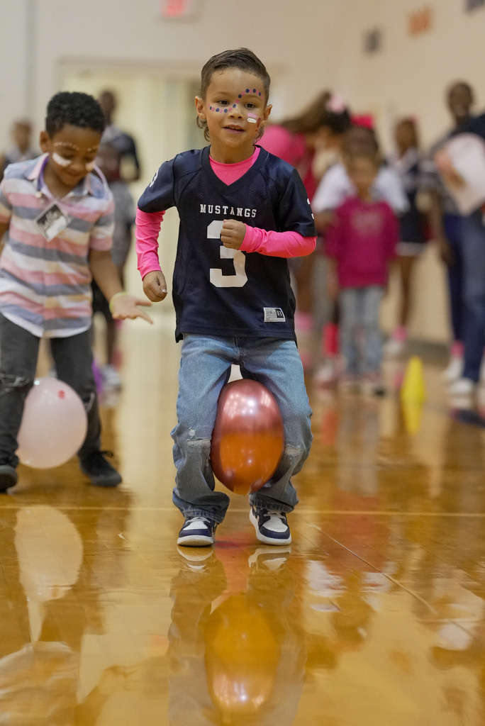 boy holding a balloon between his knees racing