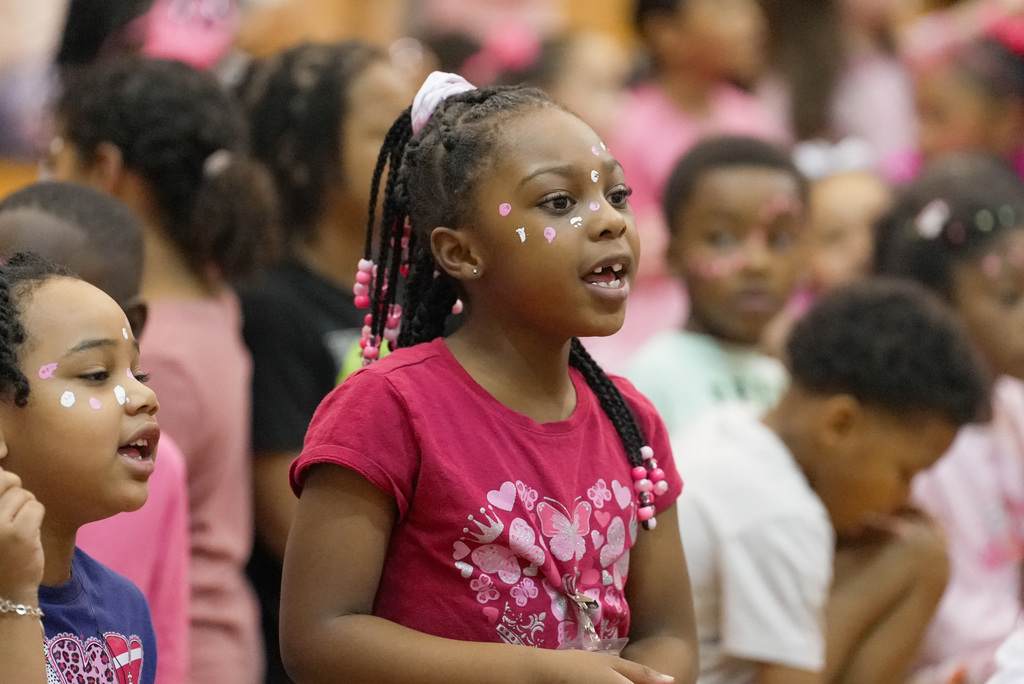 girl dressed in Pink Out clothes and facepaint cheering at pep rally