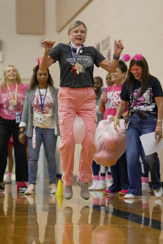 teacher jumping with a balloon between her kneeds