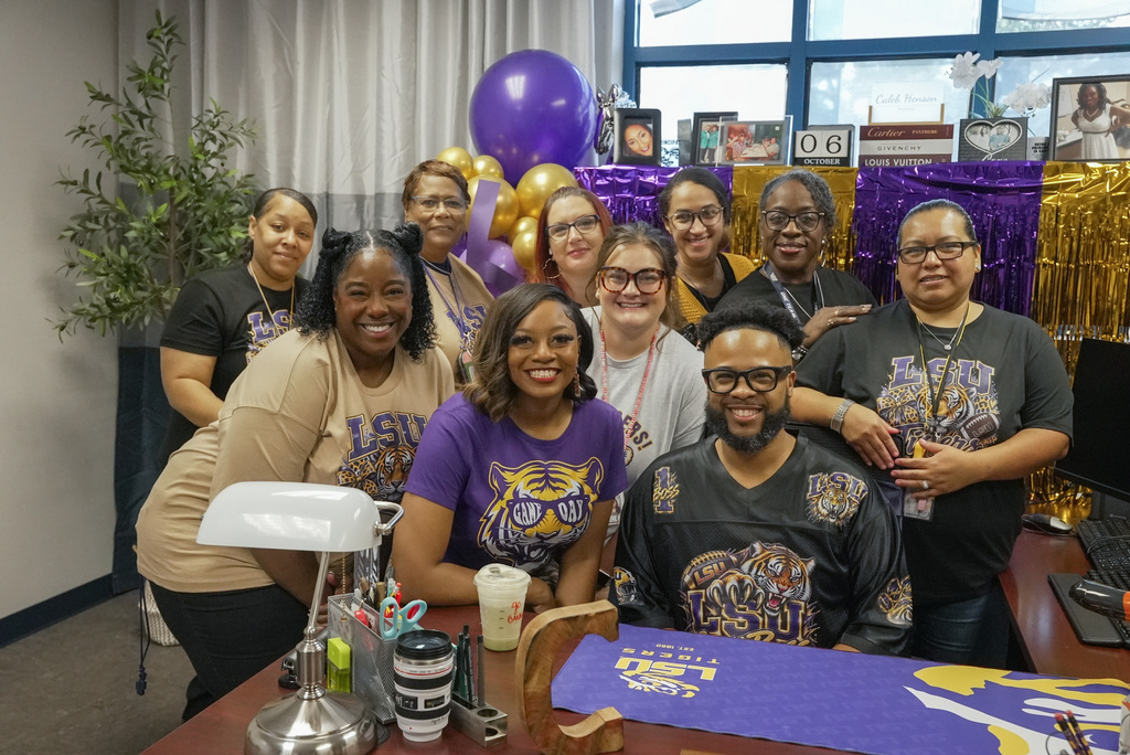 wosms staff surrounding principal in his office