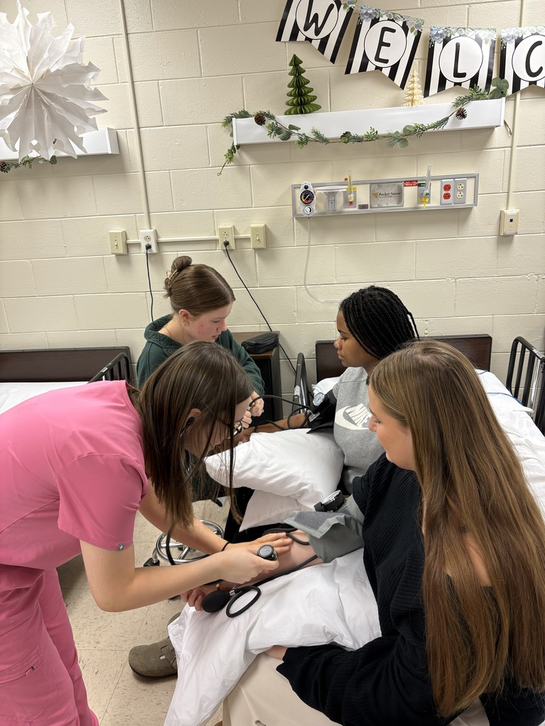 students practicing taking blood pressure on other students
