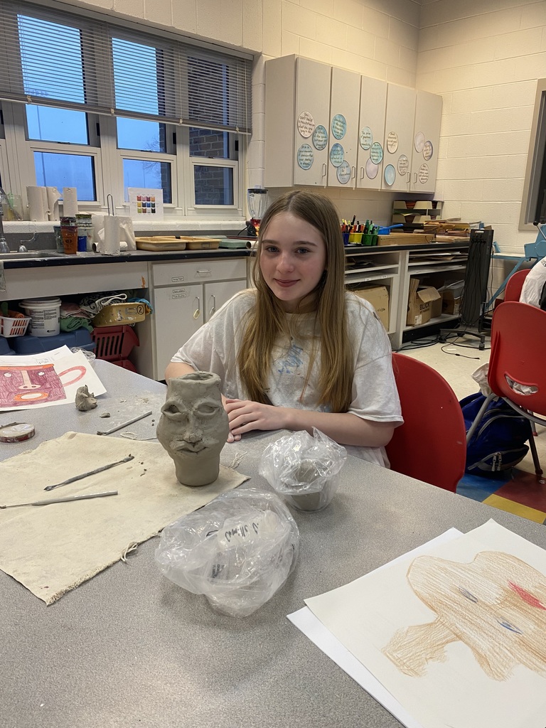 6th grade student showing off her clay mask