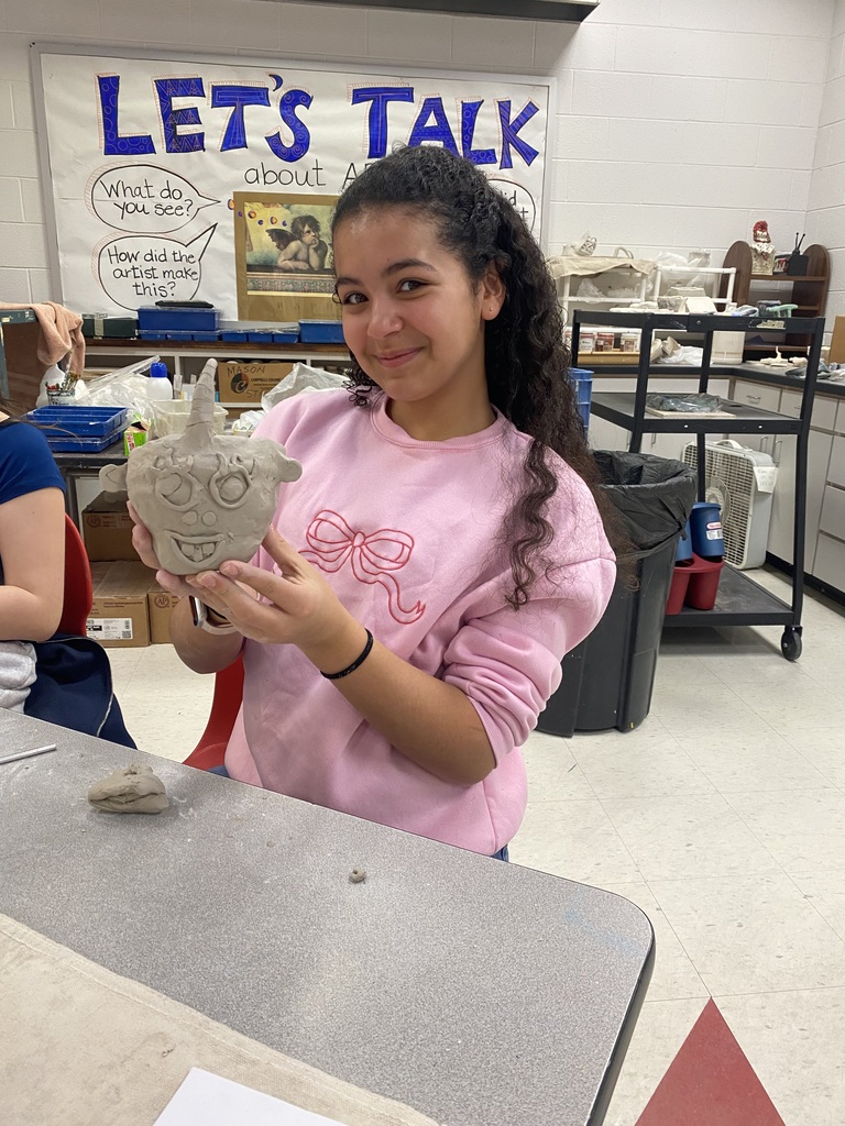 6th grade student showing off her clay mask