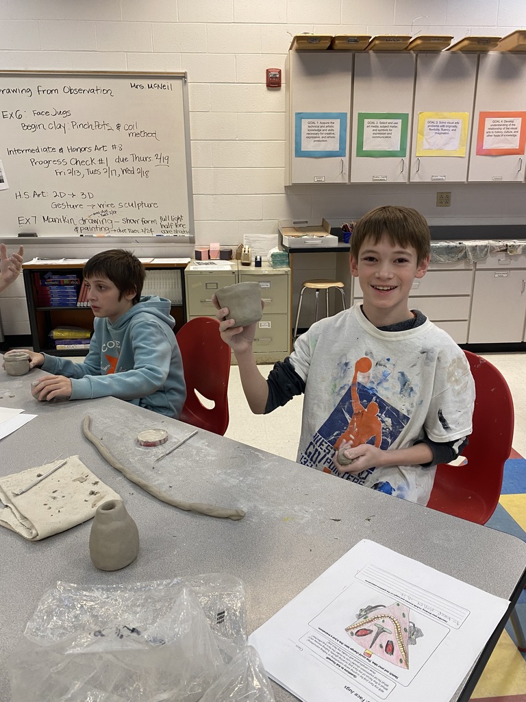 6th grade student showing off her clay mask