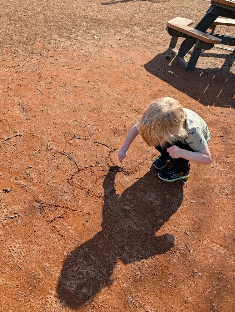 Student writing in the dirt