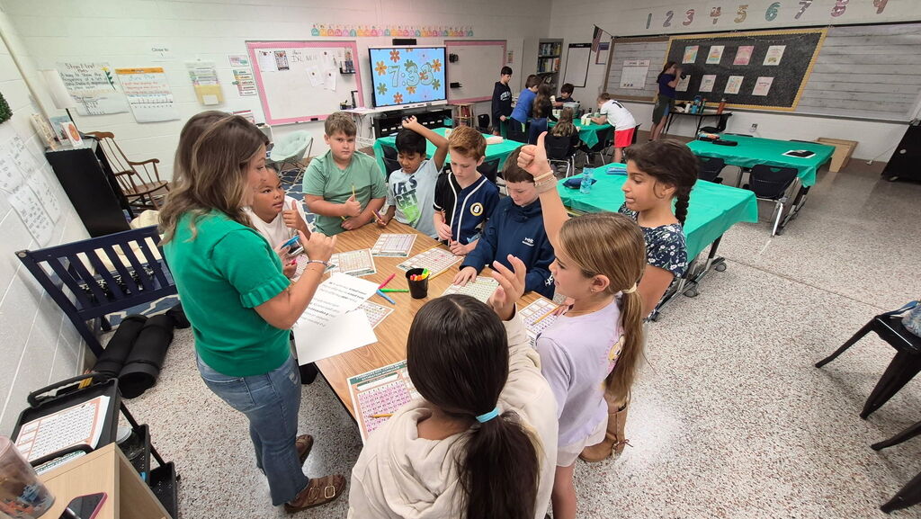 Fifth-grade students participate in Starbucks-themed learning activities, including a book tasting, stem-and-leaf data challenge, coffee bean estimation, and place value games, while enjoying themed snacks and drinks.