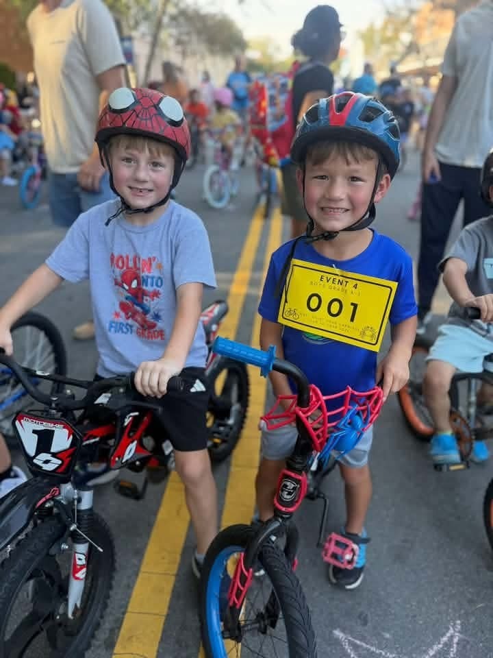 Young Pointer students ride their bicycles during the Tour de Crab community event, smiling and enjoying the ride.