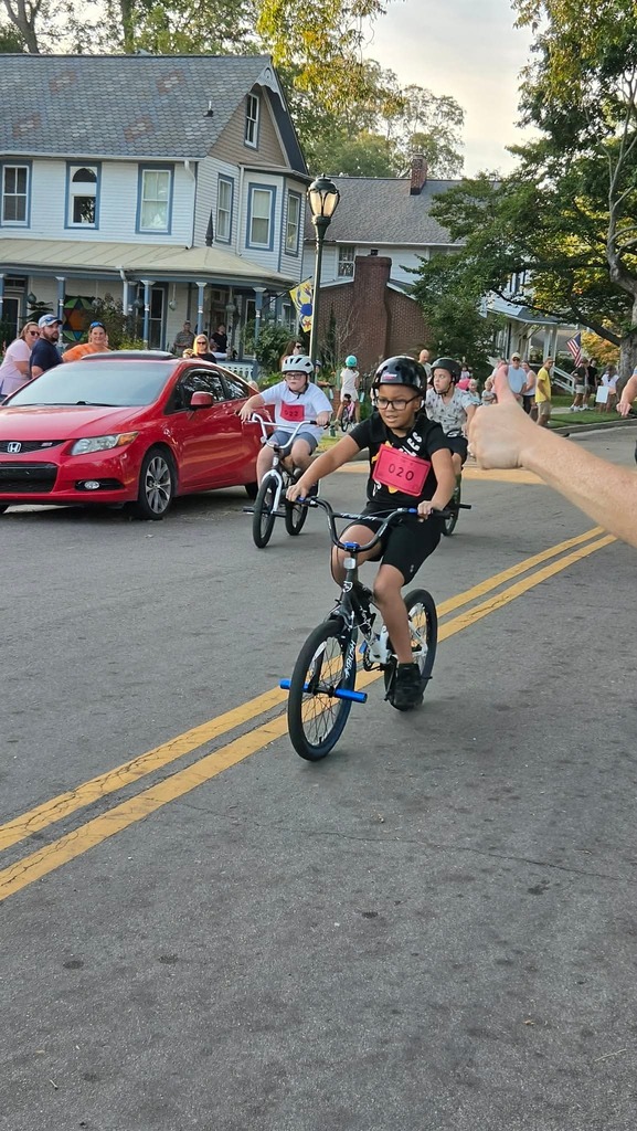Young Pointer students ride their bicycles during the Tour de Crab community event, smiling and enjoying the ride.