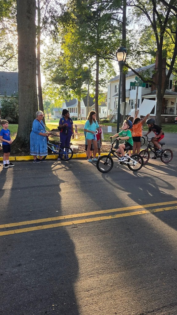 Young Pointer students ride their bicycles during the Tour de Crab community event, smiling and enjoying the ride.