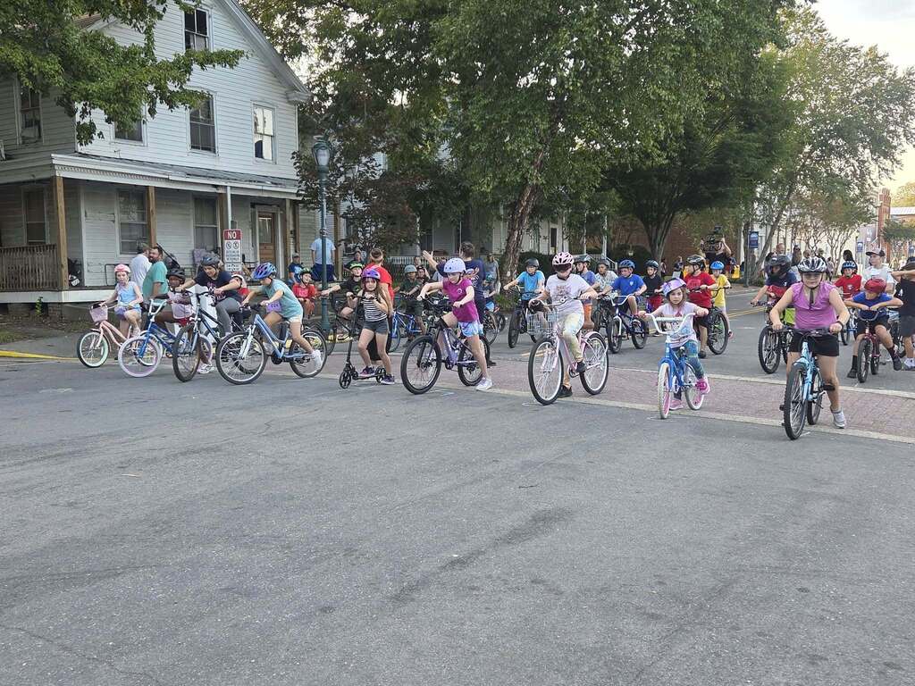 Young Pointer students ride their bicycles during the Tour de Crab community event, smiling and enjoying the ride.
