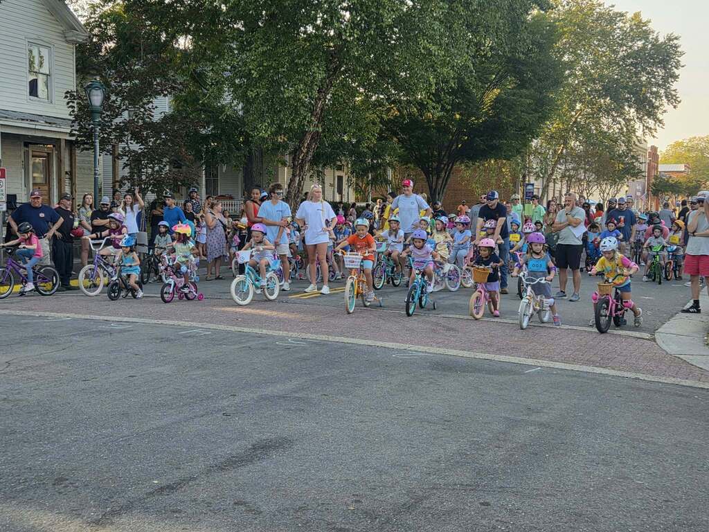 Young Pointer students ride their bicycles during the Tour de Crab community event, smiling and enjoying the ride.