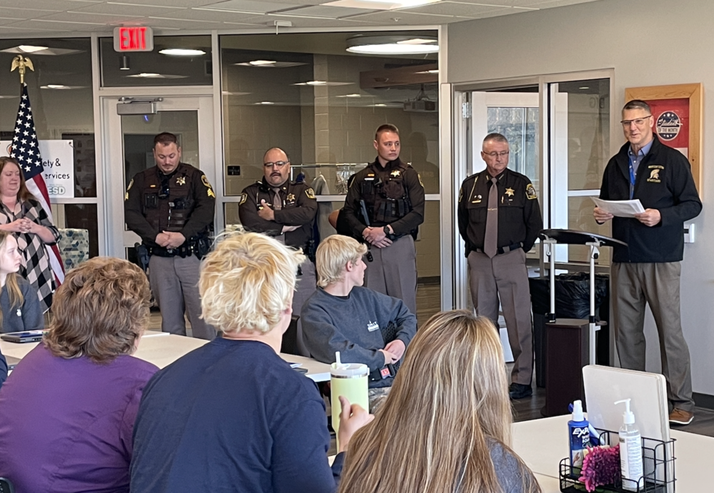Superintendent of Mason County Central Schools standing next to police officers reading a statement.