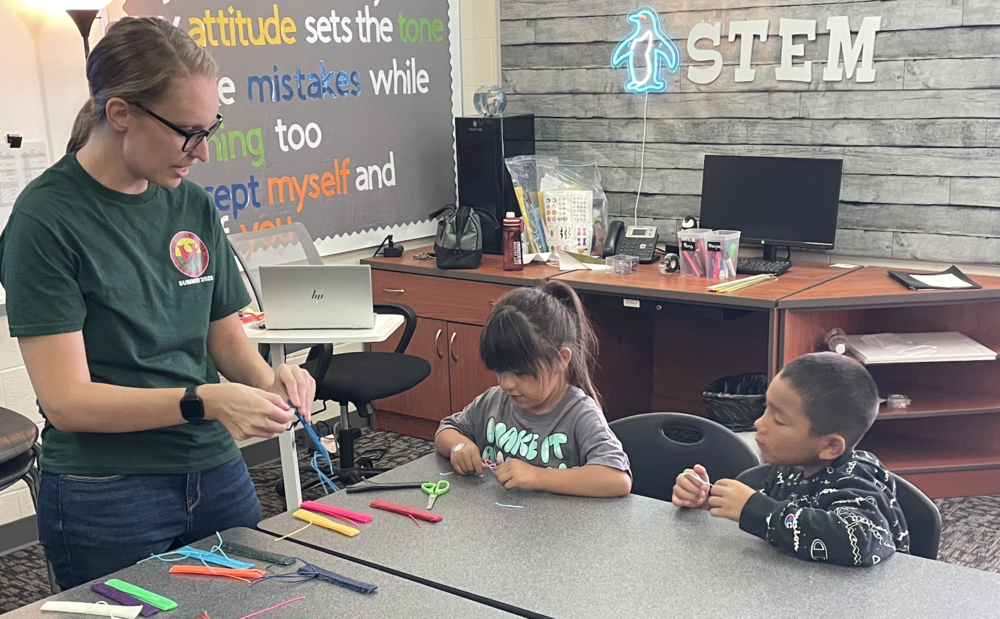Teacher working with students on a craft project.