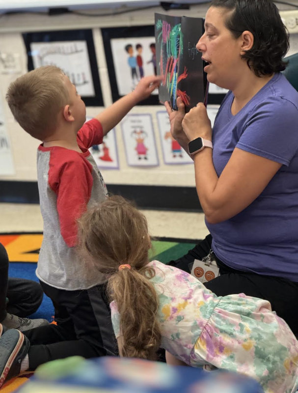 Student pointing at a picture being held by a teacher