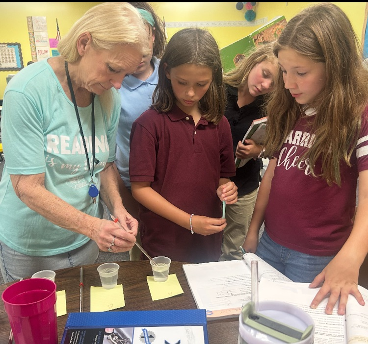 Mrs. Terry helping a couple of students with a science experiment