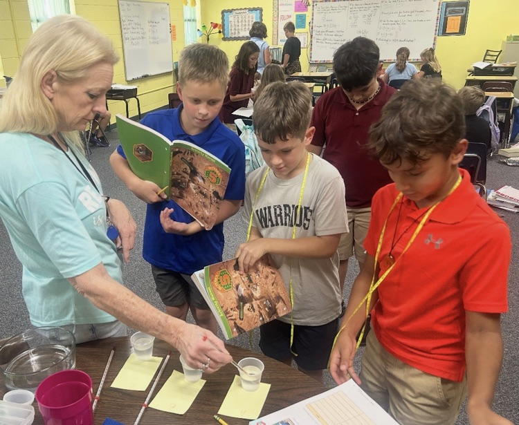 Mrs. Terry helping a couple of students with a science experiment