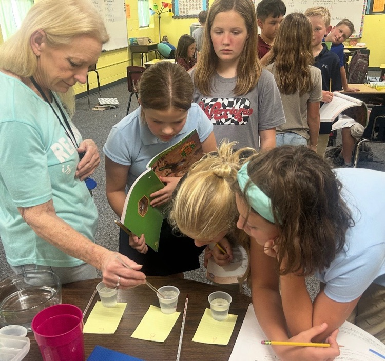 Mrs. Terry helping a couple of students with a science experiment
