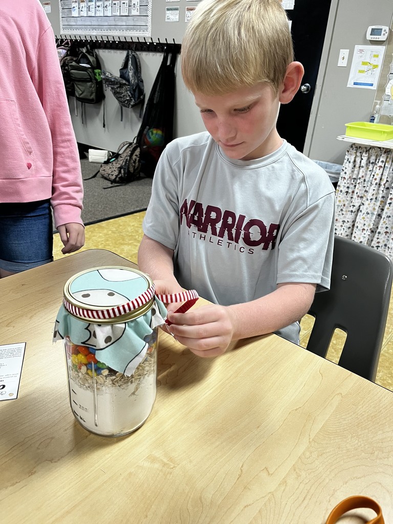 A 4th grader tying a ribbon on the cookie mix for their auction basket