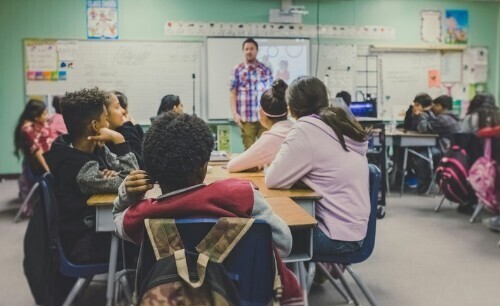 a classroom of students with their attention on their teacher at the front of the classroom