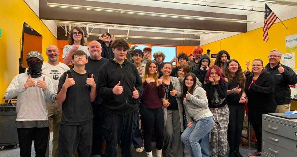 Group photo of AIA teachers and students doing the "thumbs up" gesture