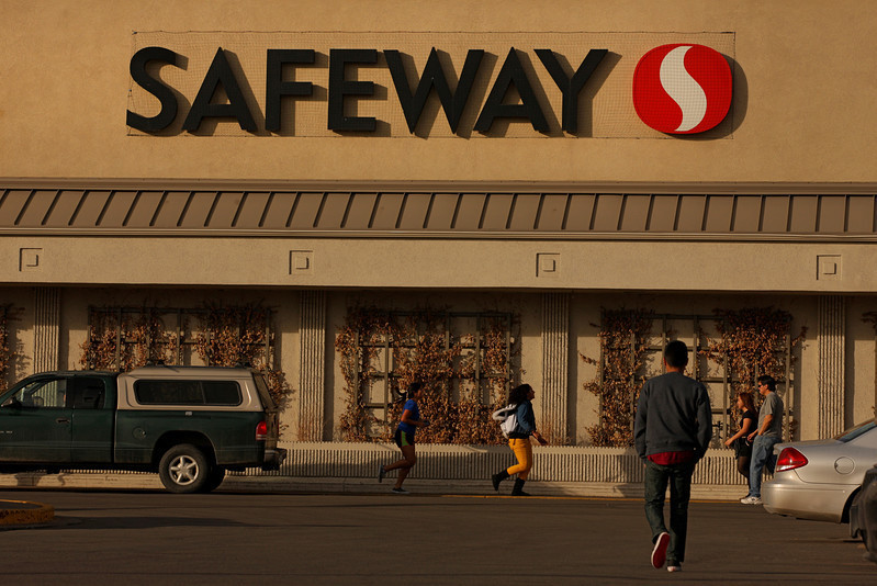 People in a parking lot walking into a Safeway grocery store