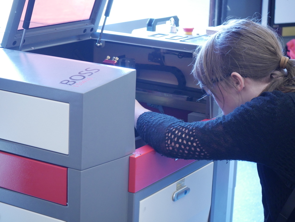 Student taking a look at their work in the laser cutter