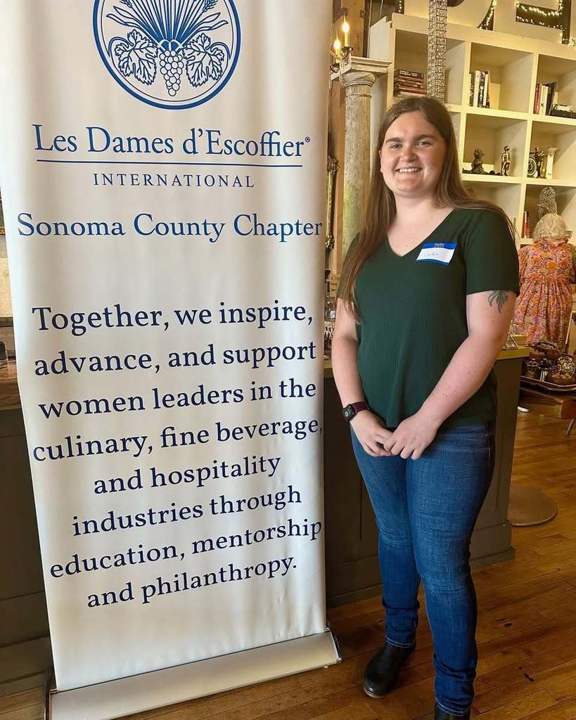 Carlee Austin poses in front of a banner for Les Dames d'Escoffier 
