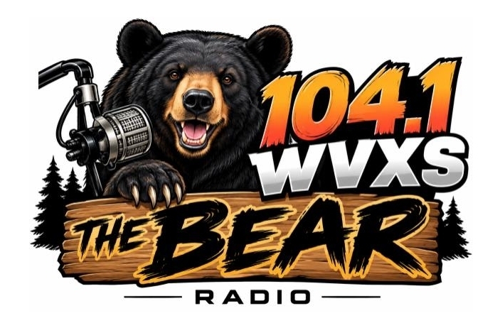 104.1 WVXS The Bear Radio logo featuring a smiling black bear wearing headphones beside a vintage microphone. Bold orange and white lettering reads “104.1 WVXS,” with “The Bear” displayed on a wooden sign and “Radio” underneath. Black pine trees complete the design.
