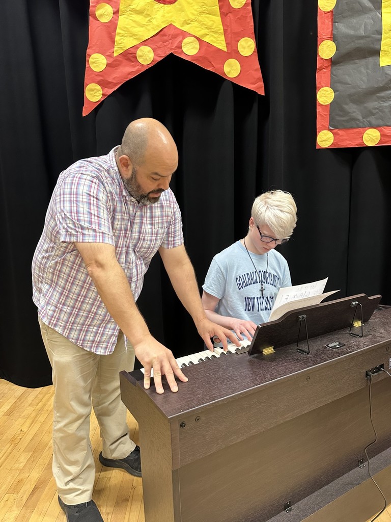 A male instructor assists a male student with the piano.