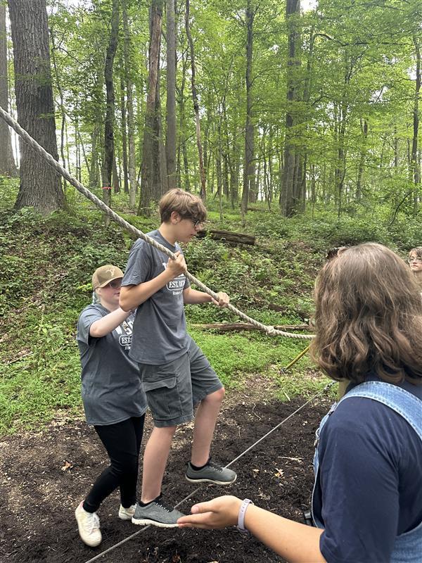 A male camp participant holds onto a piece of rope during the rope course activity.