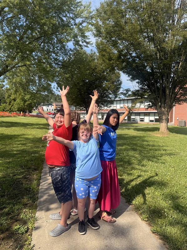 Camp participants stand in a circle while holding up their arms. 