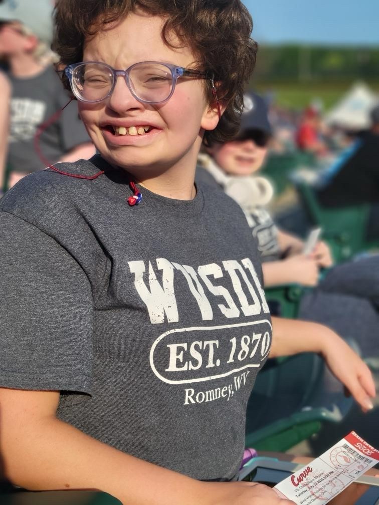 A camp participant wearing a gray-colored shirt smiles proudly for the camera. 