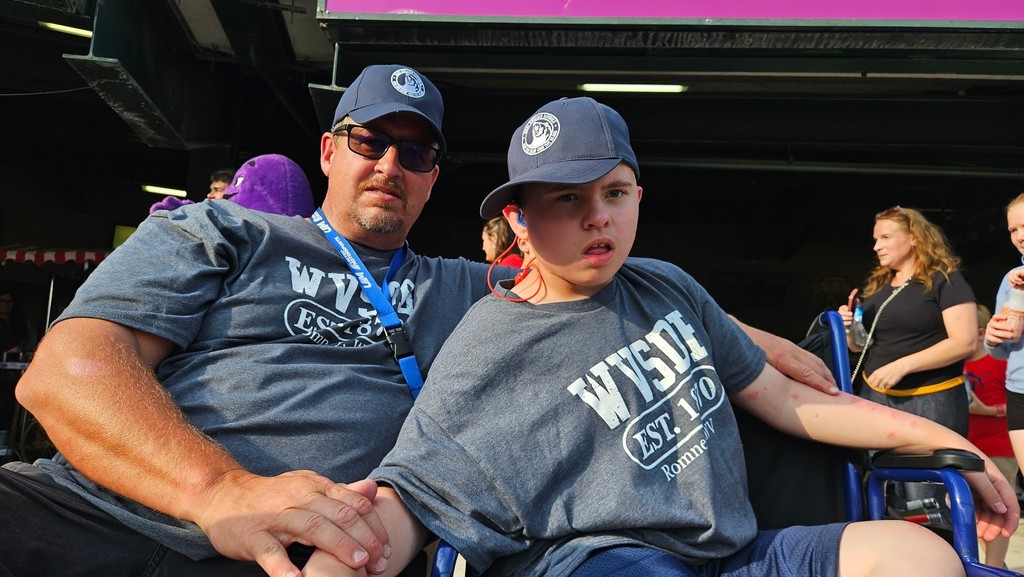 A male residential care specialist is seated beside a male student. 