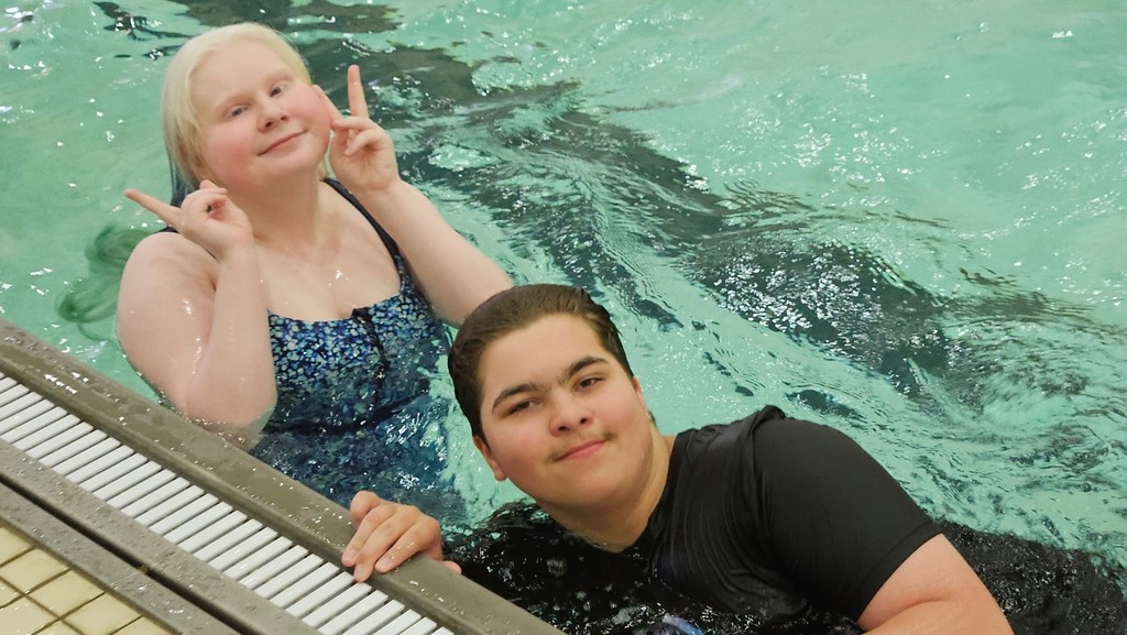 Two camp participants pose for the camera while in the pool. 
