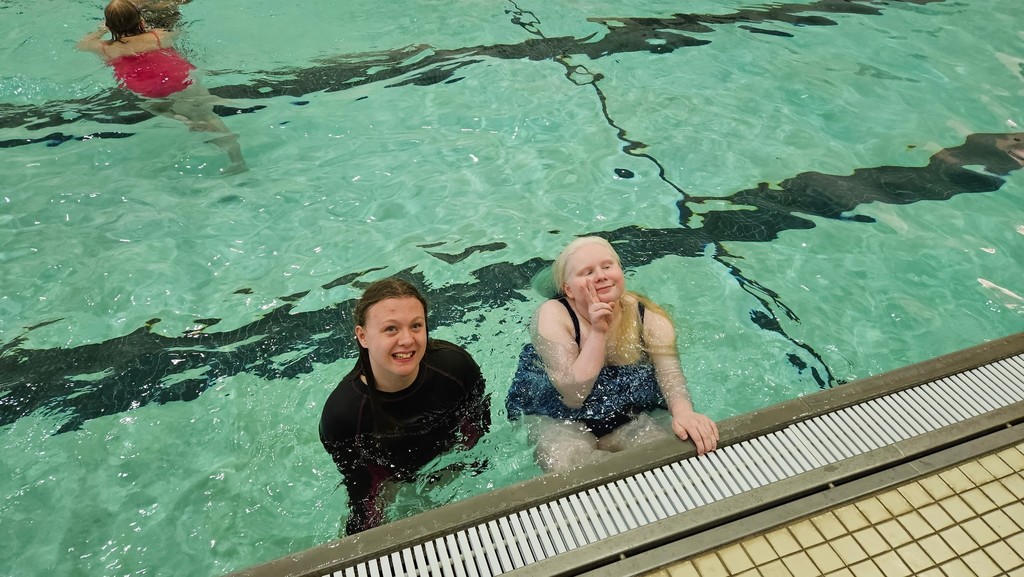 Two female camp participants swimming next to each other in the pool. 