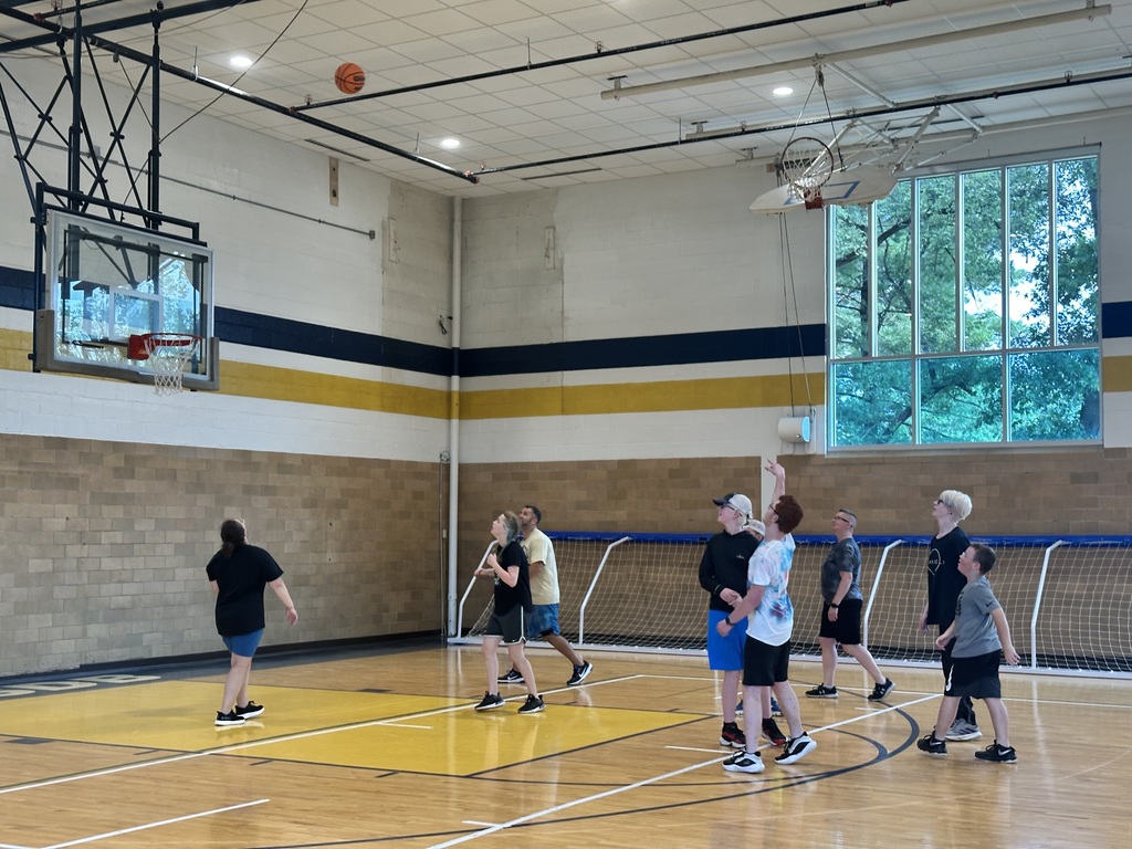 Camp participants watch where the orange basketball is going after someone threw it towards the basketball hoop. 