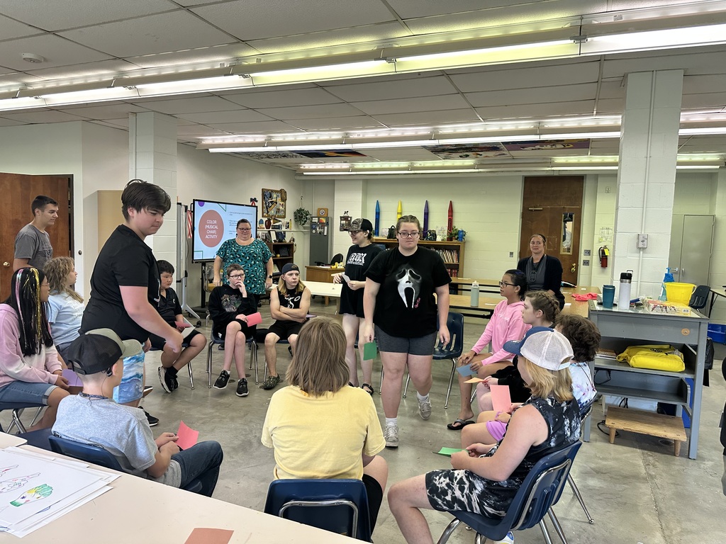 Camp participants are seated in a circle during an ASL activity. 