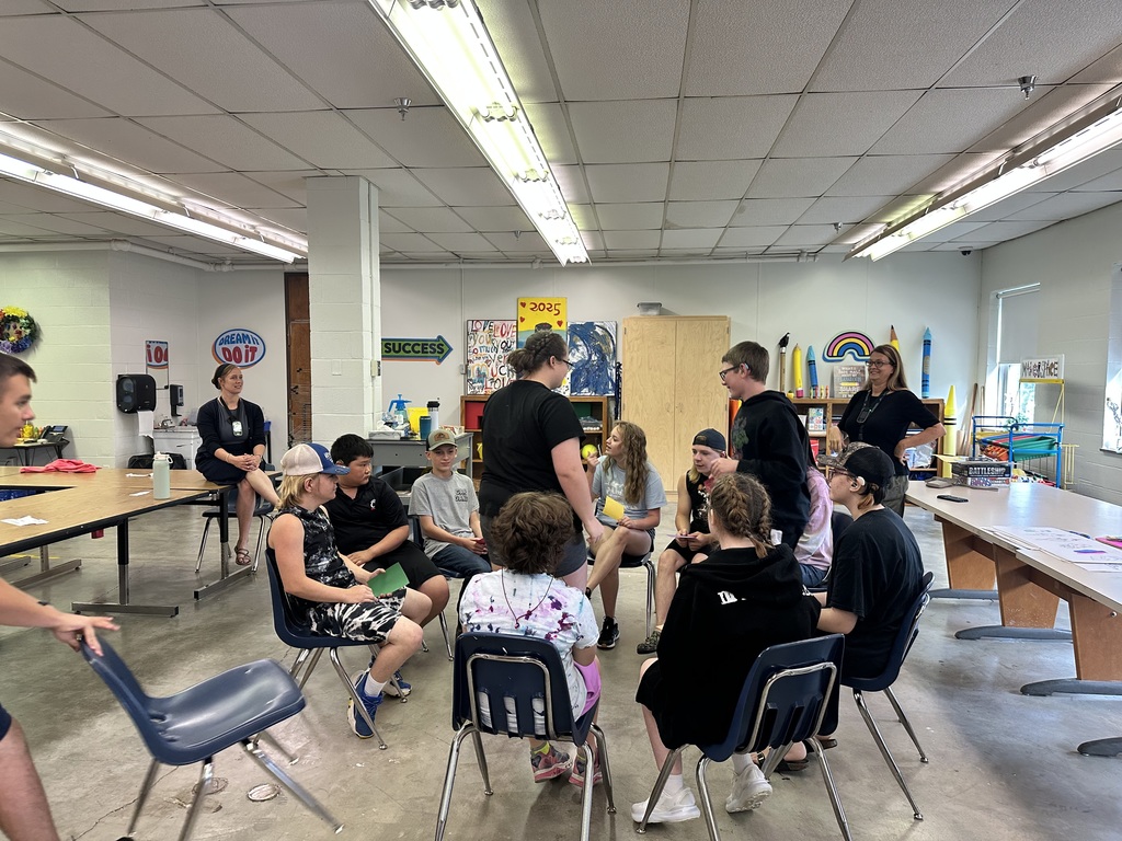 Camp participants are seated in a circle during an ASL activity. 
